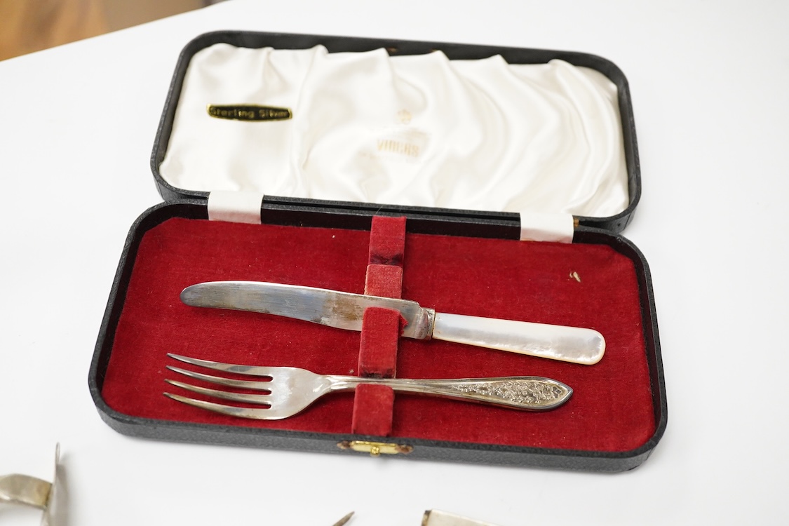 A small quantity of assorted small silver and plated flatware, a small silver stand, a silver napkin ring and a pair of modern silver mounted dwarf candlesticks.